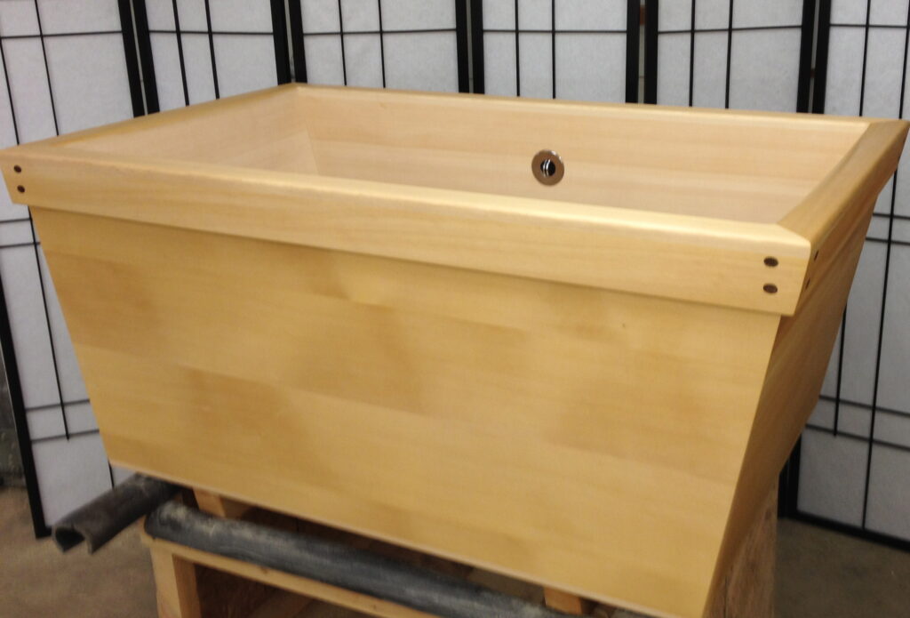 Kyoto style Hinoki Ofuro soaking tub with custom extra wide rim. The corners of the rim are pinned together with dowels made from dark hardwood contrasting with the light hinoki.