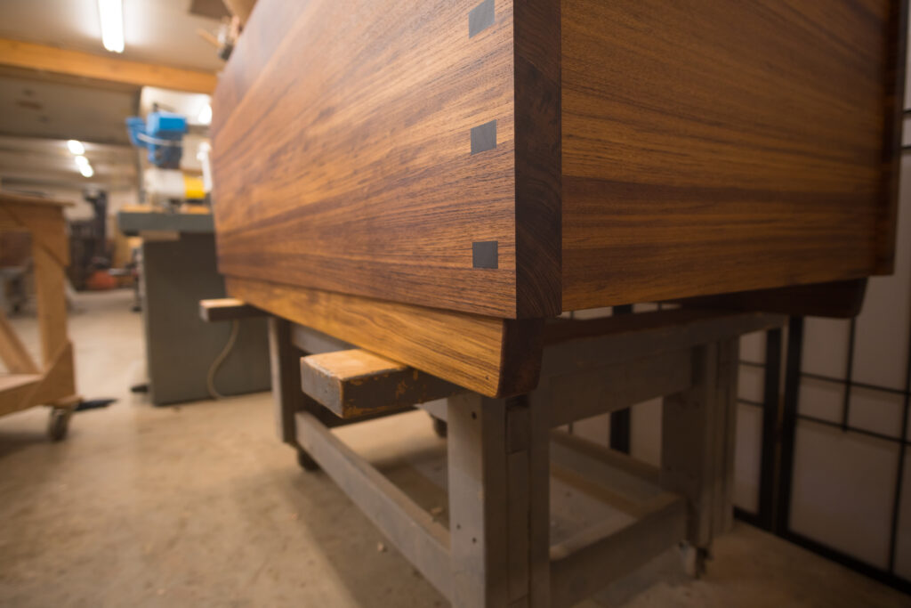 Close up view of a custom teak ofuro showing Ebony inlays covering the hidden steel bolts reinforcing the epoxied mortise and tenon joints.