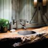 Deck mount Waterfall Sink Faucet in Rustic Nickel finish. Installed in a live-edge wood countertop with a stainless sink.