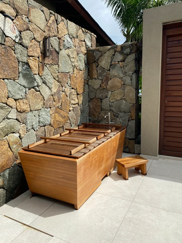 72 x 36 Zen Bathworks Teak Kyoto Ofuro soaking tub with cover and bathing stool outdoor installation by a stone wall